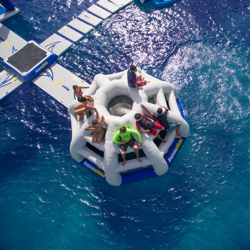 People lounge and play on the Thunderdome inflatable, floating over deep blue water.