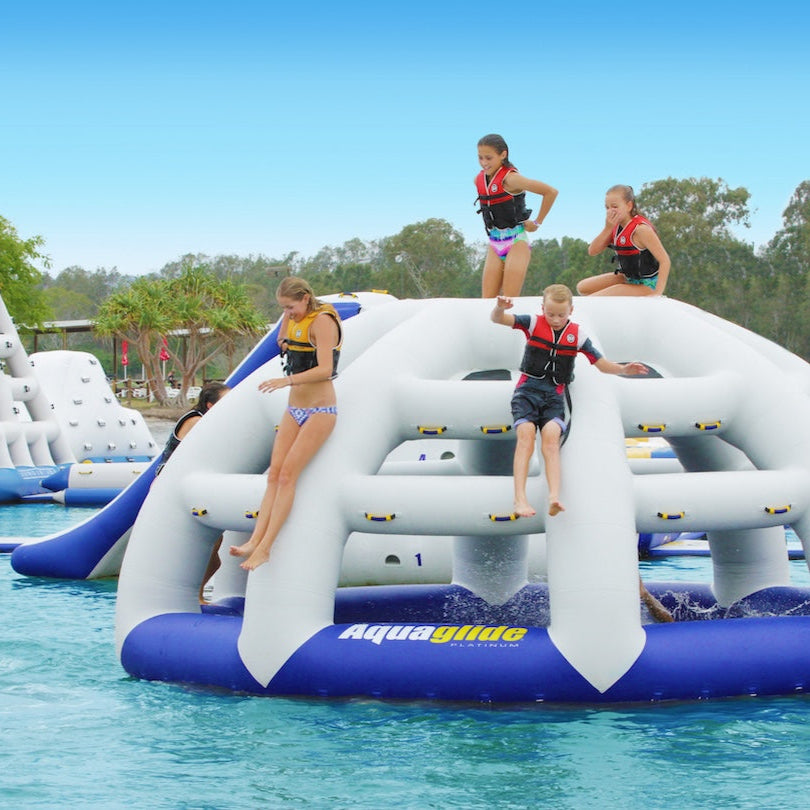 Children leap and drop from the Thunderdome inflatable into the water below.
