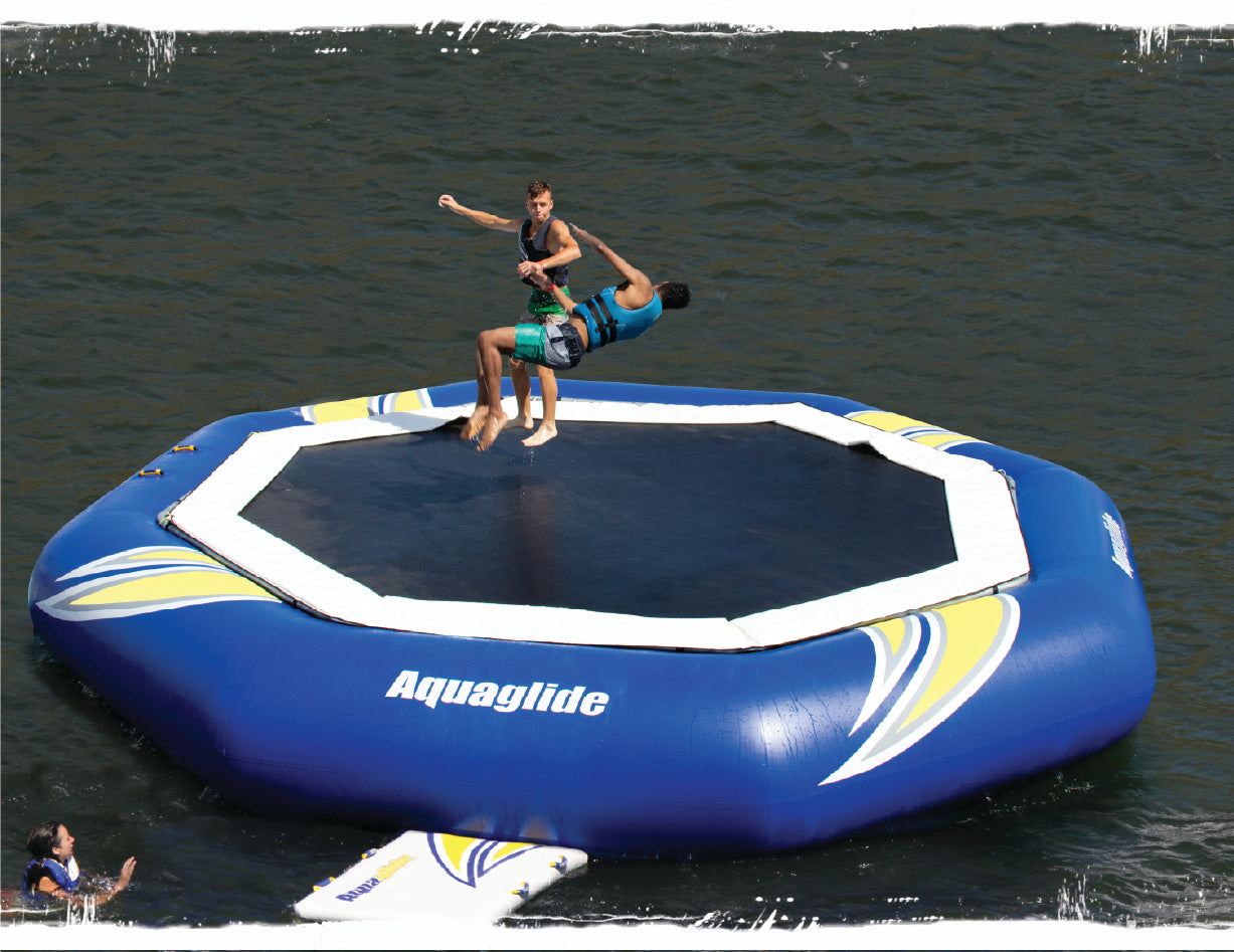 Two guys jumping on a water trampoline.