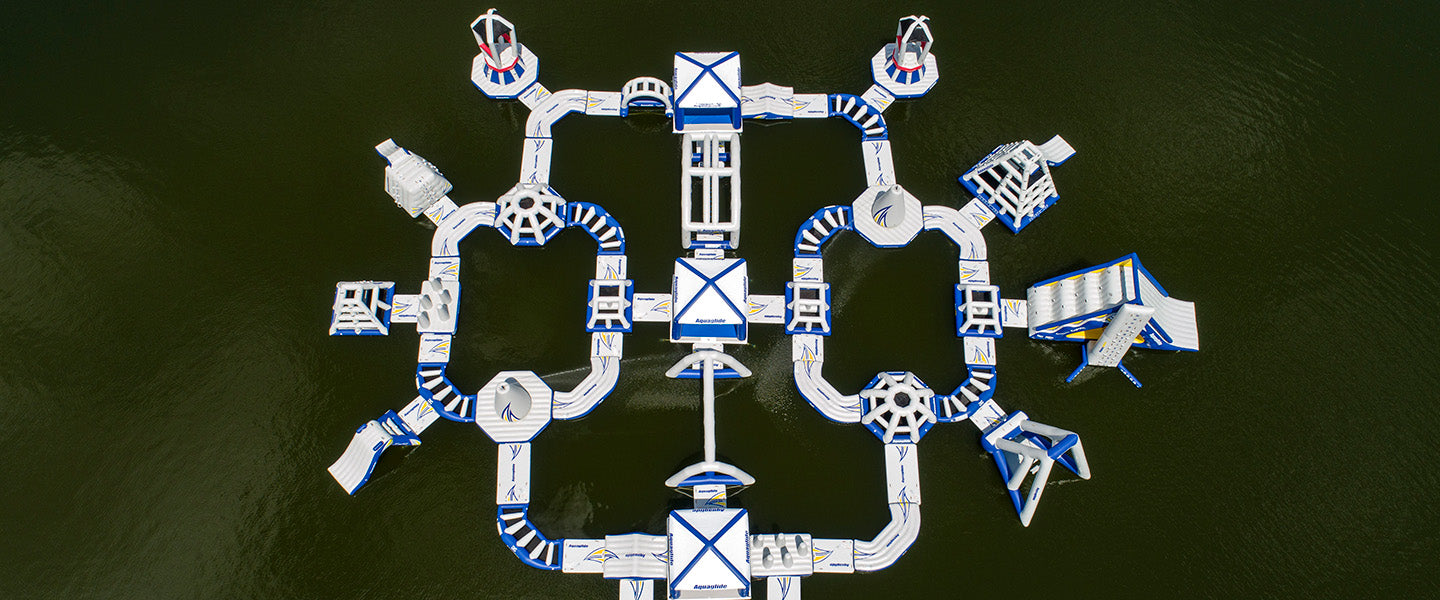 Aerial view of inflatable water park with interconnected structures on dark water.