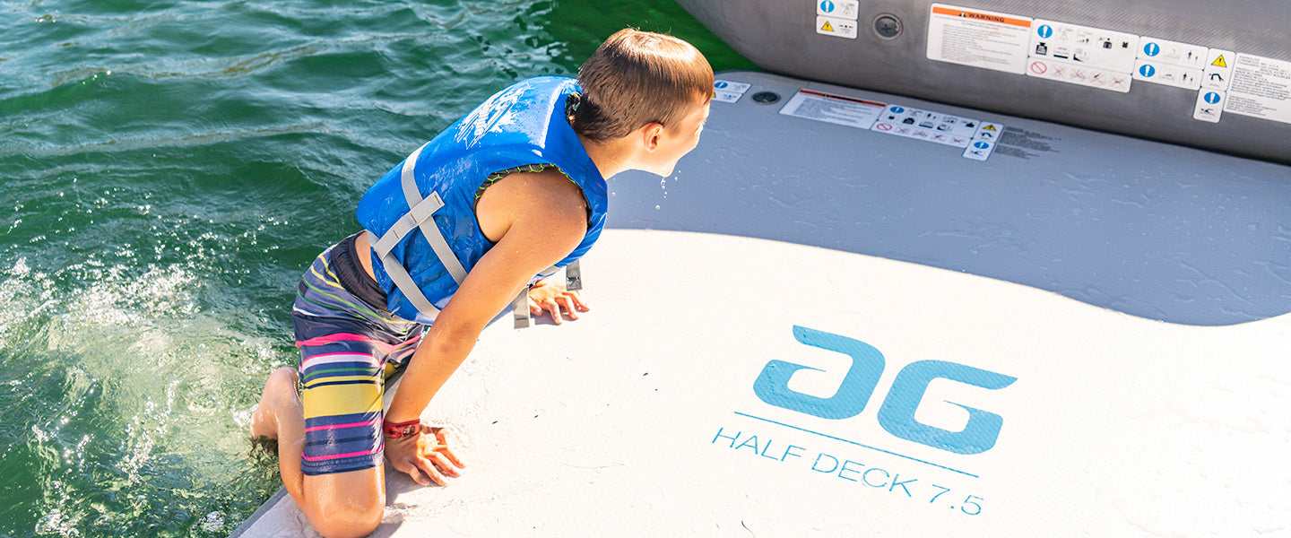 Child in life jacket climbing onto a boat deck with colorful shorts.
