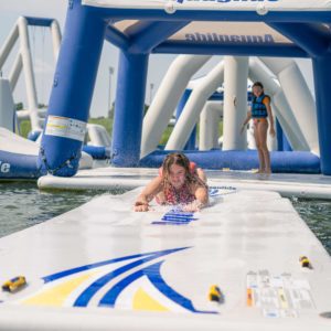 A teen girl slides down the speedway 20 on her stomach while water splashes around her