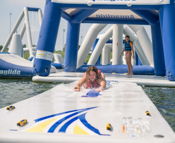 A teen girl slides down the speedway 20 on her stomach while water splashes around her