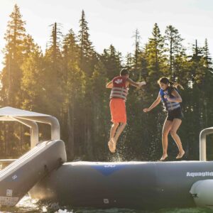 Siblings jump on a water trampoline in the fading afternoon light