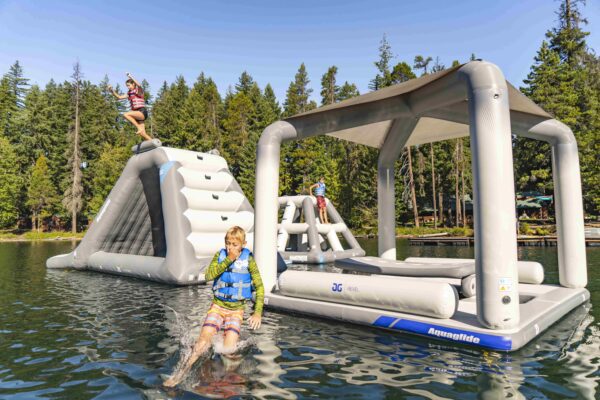 Siblings jump off the Velocity slide and Revel Lounge on a small lake