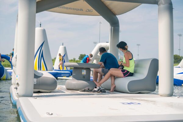 Parents watch their kids play on the aquapark in the background while resting on the OG lounge