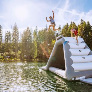The velocity slide shot from the side as a teen girl jumps from the side on a scenic mountain lake