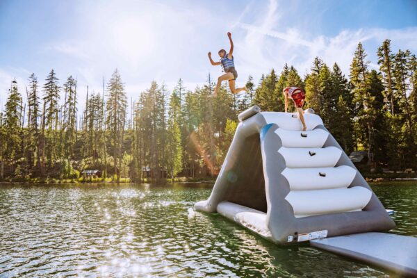 The velocity slide shot from the side as a teen girl jumps from the side on a scenic mountain lake