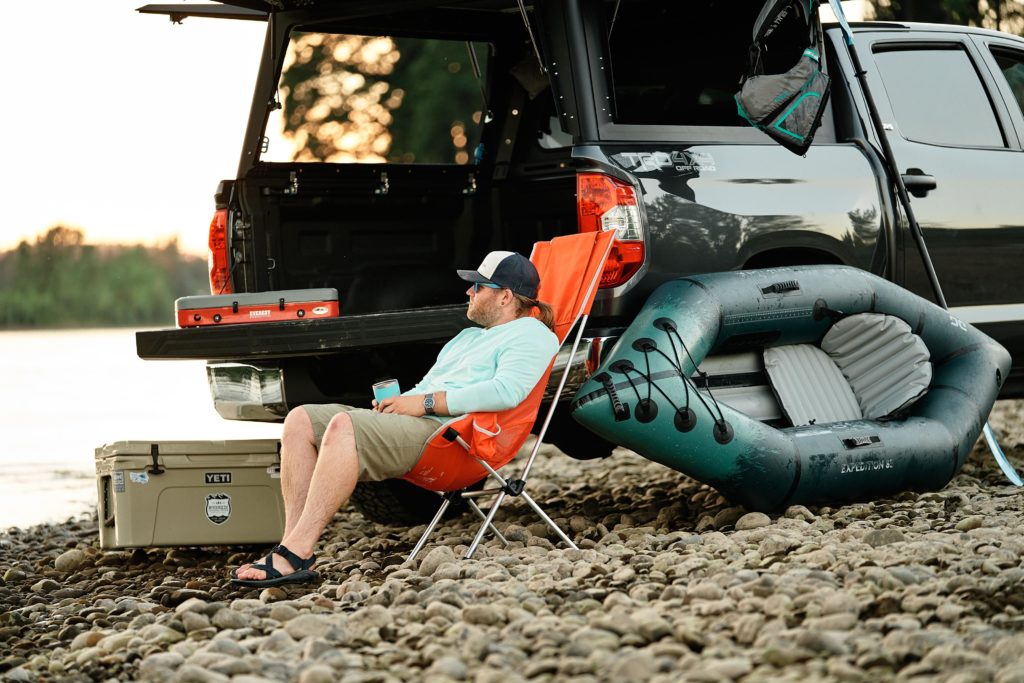 Paddler sitting in a camp chair next to a truck and the Backwoods Expedition 85